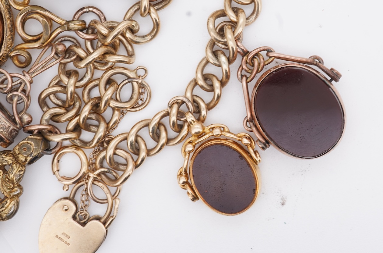 A 1970's 9ct gold curb link charm bracelet, with 9ct gold heart shaped clasp, hung with seven assorted gold or gilt metal mounted charms including six chalcedony set fob seals, gross weight 73 grams.